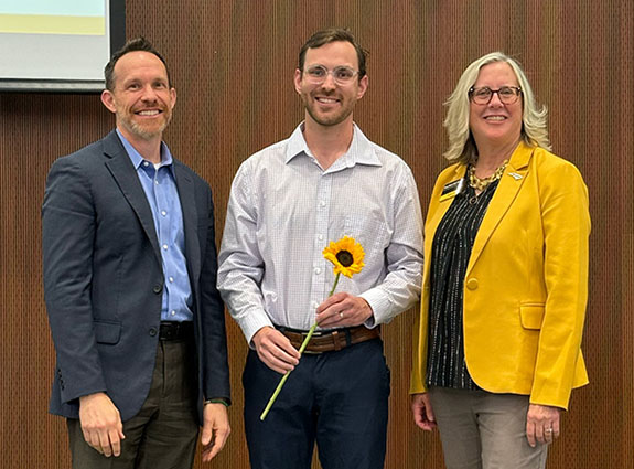Award winner AJ Britton (center) stands with Dr. Mark Trahan and Dean Marie Huff