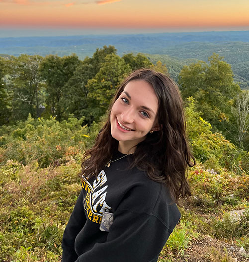 Elizabeth Haslam smiles in front of a mountain sunset