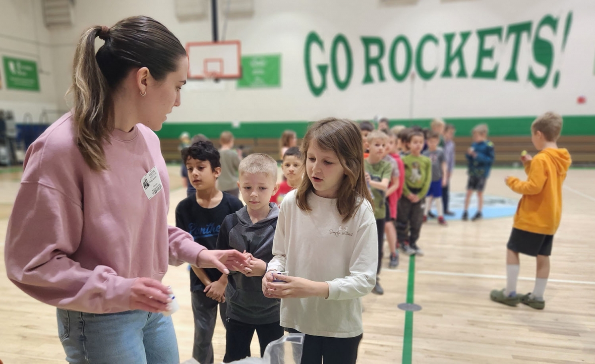 Nutrition Grad Student Emily Bowles provides a sample cucumber to a student at Blowing Rock Elementary