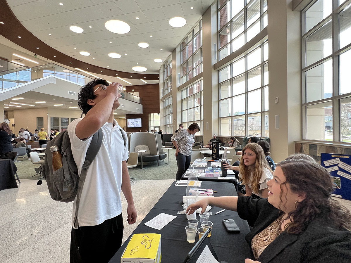 Student swallows a slurry mixture at CSD table during IPE Fair