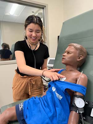 High school student Kimberly Mai listens to breathing in nursing simulation lab