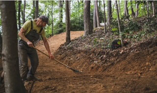Kristian Jackson raking a trail at Rocky Knob
