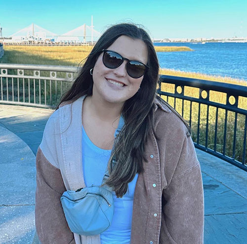 Madison Wood smiles in front of a bridge and water