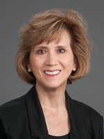Woman with brown hair wearing a blazer who is smiling
