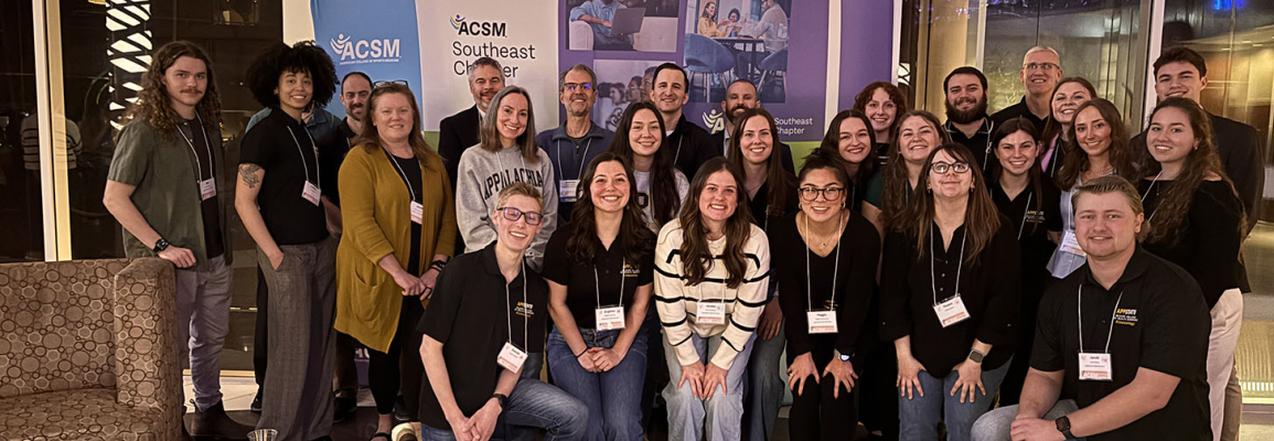 Large group of men and women are standing together in rows smiling
