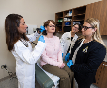 Doctor of Nursing Practice-Family Nurse Practitioner program faculty members Dr. Melissa Viatori, clinical assistant professor in App State’s Department of Nursing, far left, and Dr. Melinda Bogardus, assistant professor in the nursing department, second from right, instruct App State senior nursing major Kimber Blackburn, of Clayton, far right, during an experiential learning experience in the Beaver College of Health Sciences’ nursing skills lab in the Levine Hall of Health Sciences. Melissa Edmondson, administrative assistant in the Department of Nursing, second from left, played the role of patient during the exercise. Photo by Chase Reynolds Women in white coat looks inside a woman's ear while two other clinical people look on.