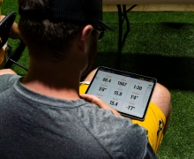 Baseball player looks down at a screen showing his pitching stats 