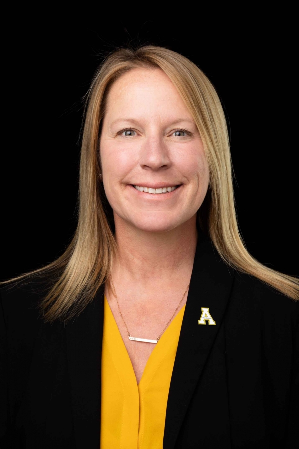 Image of a woman wearing gold shirt and black blazer