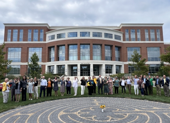 Group of people with a labryinth in front of them and a large brick building behind them