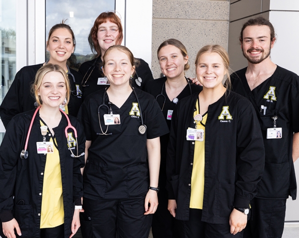 Group of people wearing App State scrubs stand together 