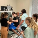 Group of students listen to a manikin's chest as part of a summer healthcare program at App State