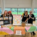 Group of young people wearing Appalachian scrubs stand at a sun safety info booth