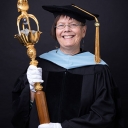 Person wearing regalia and holding a large wooden staff
