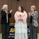 Student stands between two faculty members as they applaud