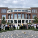 Group of people with a labryinth in front of them and a large brick building behind them