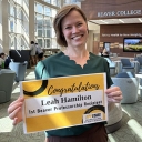 Woman smiles and holds a sign that says Inaugural Beaver Professor