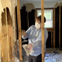Woman wearing a mask helps remove insulation from a home. 
