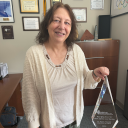 Woman stands with large crystal trophy inside an office