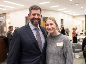 Man stands with student at an event with people in the background