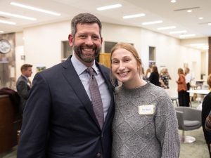 Man stands with student at an event with people in the background 