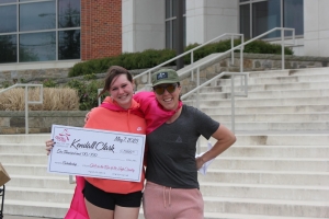 Kendall Clark holds scholarship check with GOTR Board Chair Ashley Galleher