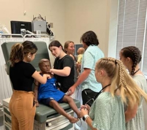 Group of students listen to a manikin's chest as part of a summer healthcare program at App State