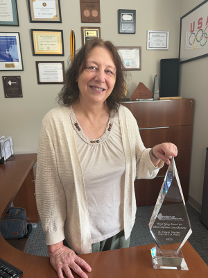 Woman stands with large crystal trophy inside an office