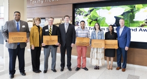 Group of people standing shoulder to shoulder, several are holding cutting boards with their names on them.