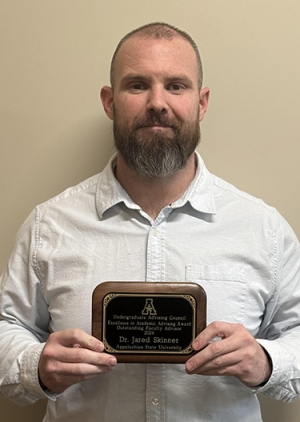 Man holds an award plaque 