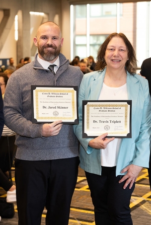 Two individuals holding certificates
