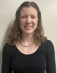 Ella Billingsley Young woman with curly dark hair smiles