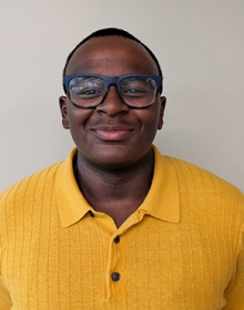 Young man wearing a bright yellow sweater and blue glasses